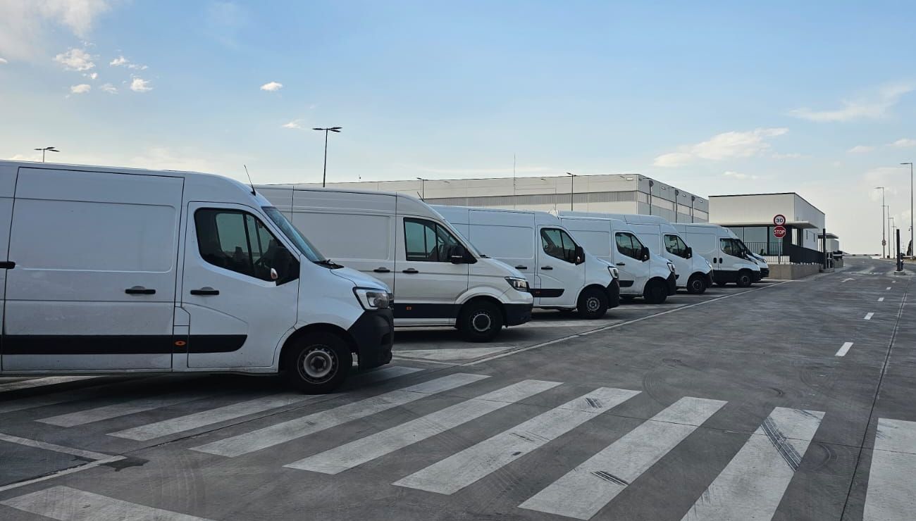 Furgonetas blancas aparcadas en fila en un polígono logístico de Madrid